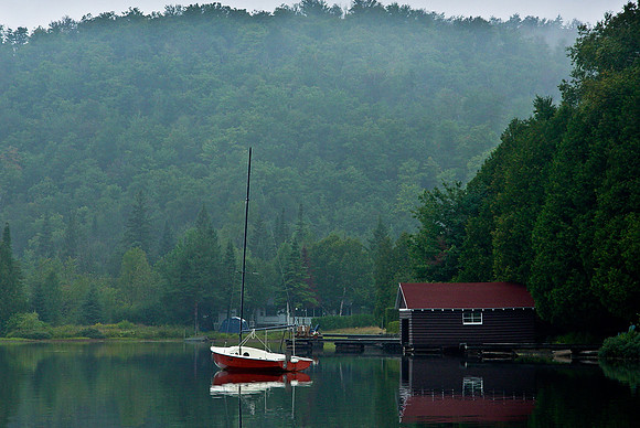 SAILBOAT ON LAKE BY BOATHOUSE